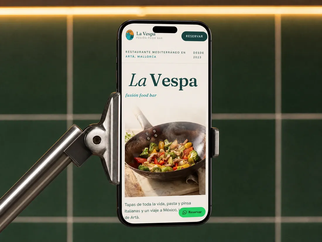La web de La Vespa en un móvil sujeto por una pinza, contra azulejo verde