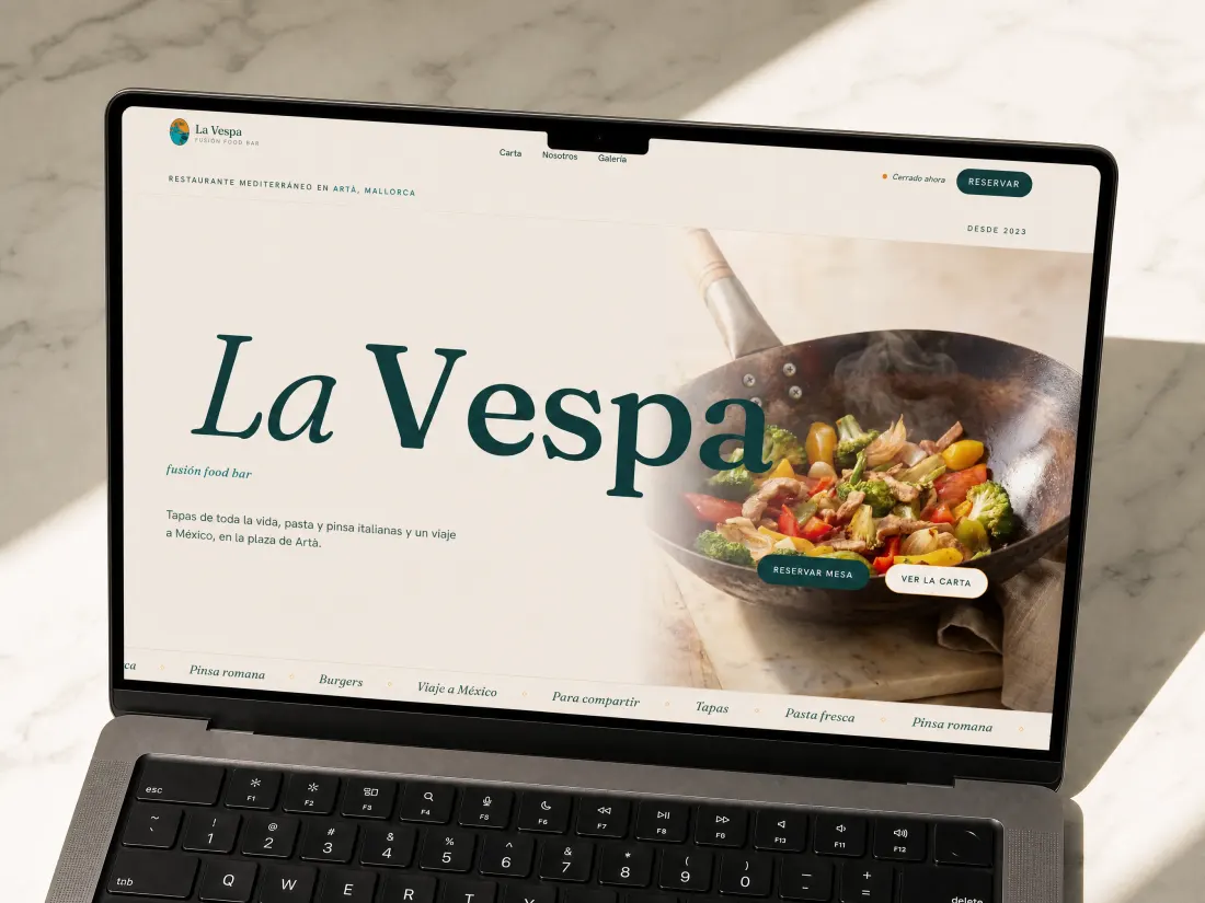 La web de La Vespa en un portátil sobre mármol blanco