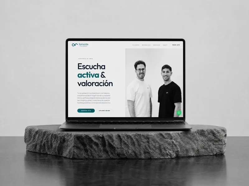 La web de Fomenta Fisioterapia en un portátil apoyado sobre una losa de piedra