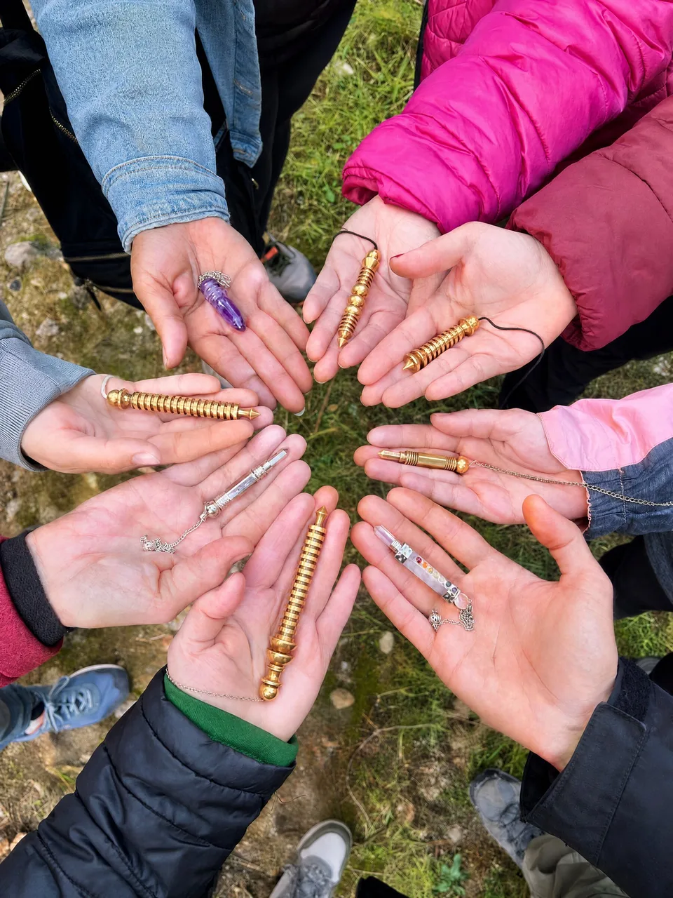 Las manos de su grupo con sus péndulos, en círculo sobre la hierba, en uno de sus talleres en el bosque